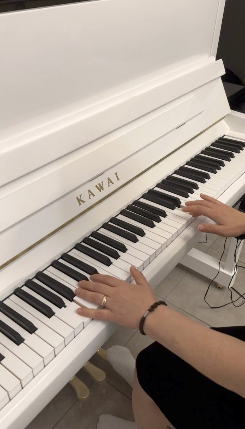 Piano Kawai blanc, mains sur le clavier